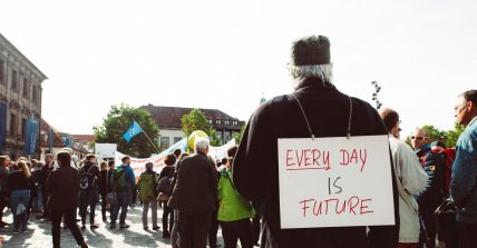 Foto di un manifestante con un cartello che recita "Every day is future"