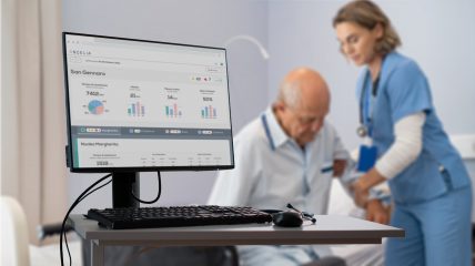 Foreground, a computer with Ancelia's dashboard; background, a nurse assists an elderly person in getting up from bed