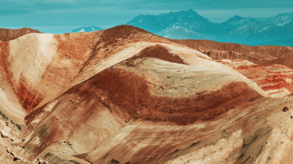 Formazioni geologiche stratificate con bande di colore sovrapposte, metafora visiva di un processo che si costruisce e si consolida nel tempo.