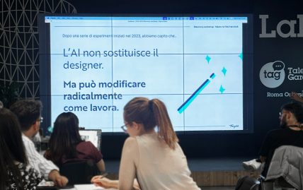 Persone in aula seguono una presentazione sullo schermo con la frase: L’AI non sostituisce il designer, ma può modificarne il modo di lavorare.