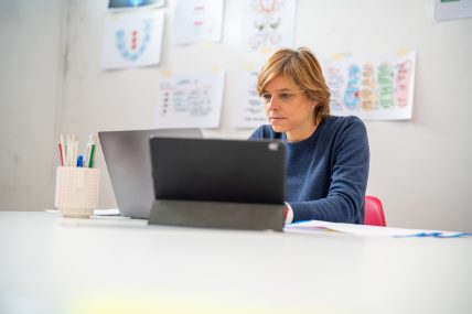 Ilaria works at the Mac, sitting at the desk