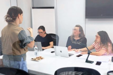 Sessione di test di accessibilità: una persona comunica in LIS, mentre tre partecipanti prendono appunti e lavorano al computer.