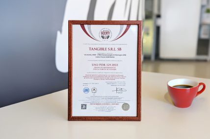 Certificato UNI/PdR 125:2022 per la Parità di Genere ottenuto da Tangible, esposto in una cornice su sfondo sfocato.