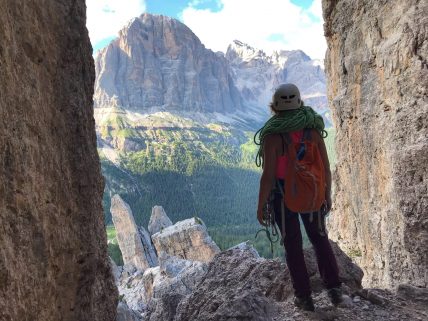 Anna in montagna fra delle rocce con una corda da arrampicata sulle spalle