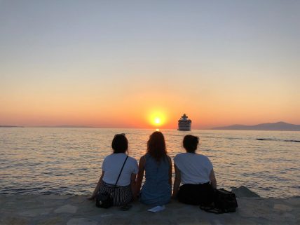 Three girls by the sea, sitting, look at the horizon