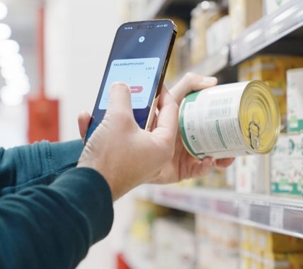 Customer in a supermarket scans a product barcode with a smartphone.