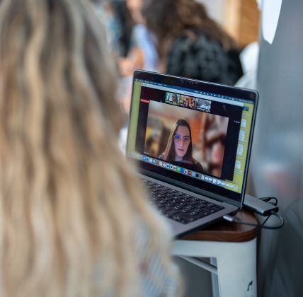 Partecipante a una videochiamata di lavoro su laptop con volti visibili a schermo.