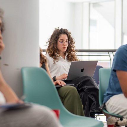 Giorgia lavora seduta con il suo laptop appoggiato sulle gambe.