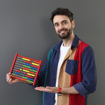 Claudio holds an abacus in his hand and smiles