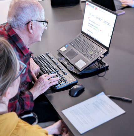 Persona anziana usa il computer con supporto, affiancato da una designer.