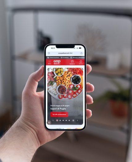 Persona tiene in mano uno smartphone con sito Coop Alleanza aperto su una promozione prodotti.