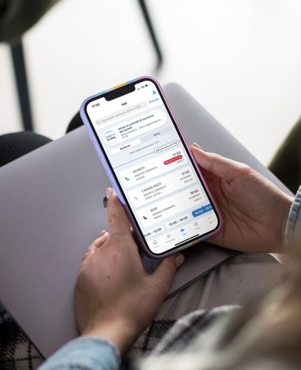 Person holding a smartphone with an airport app open on flight details.