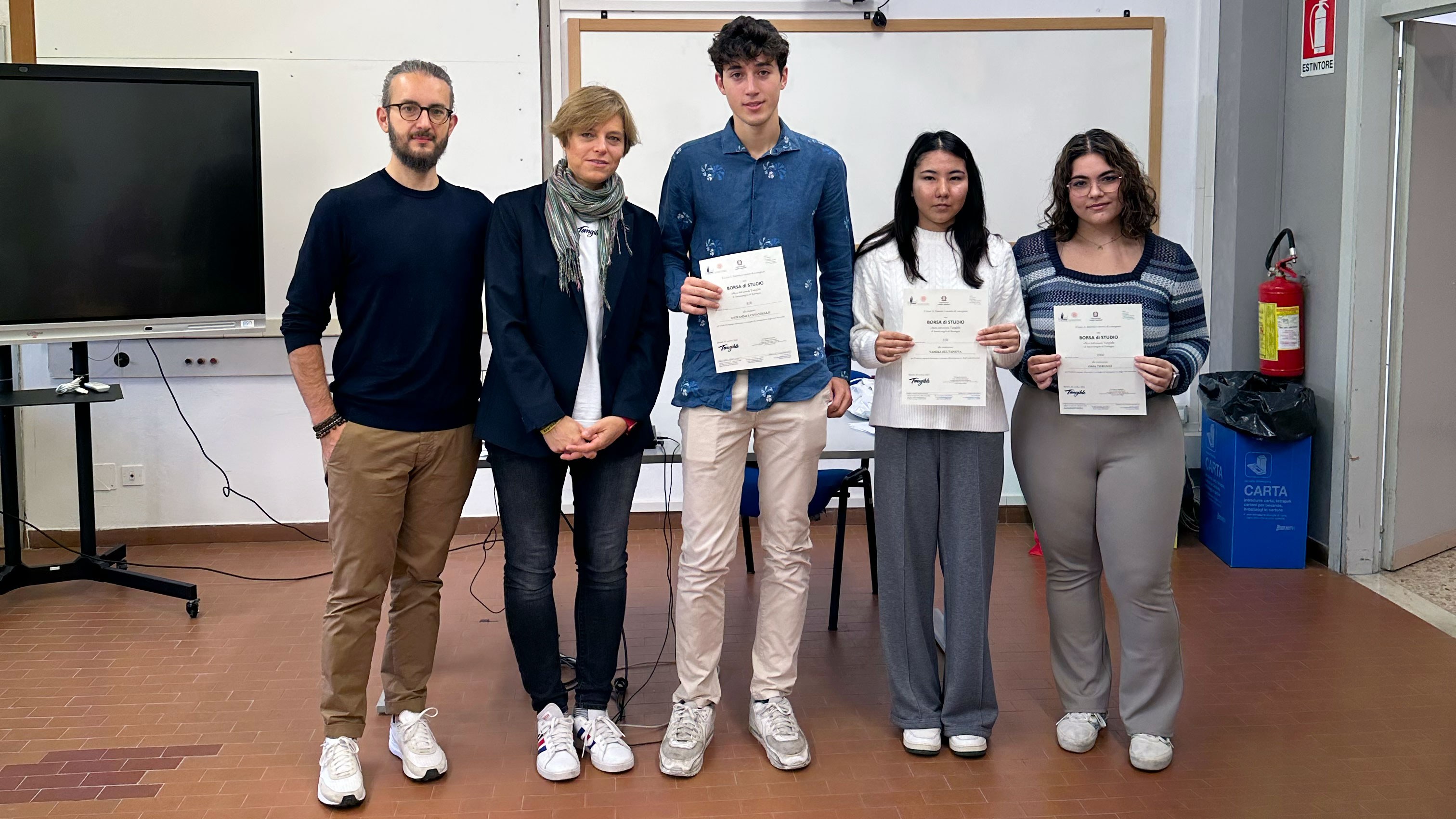 Nicolò Volpato, Ilaria Mauri and the scholarship holders pose for a photo. Each young person holds a Tangible scholarship certificate.