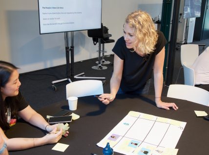 Trine Falbe, with a group of people, sitting around a table during a workshop.