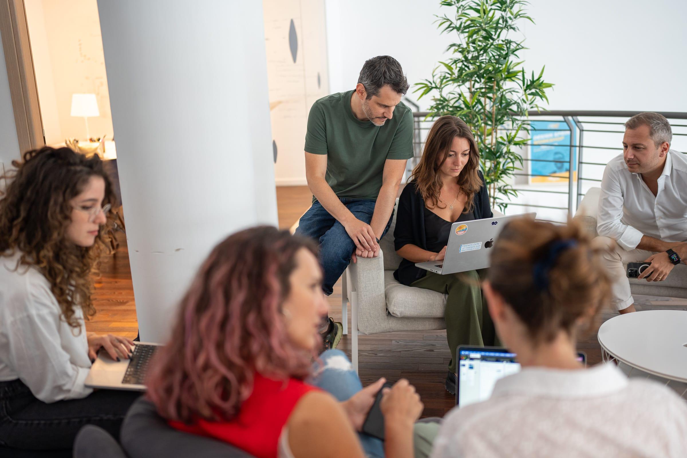 Un gruppo di persone sedute in uno spazio luminoso e moderno discute e collabora.